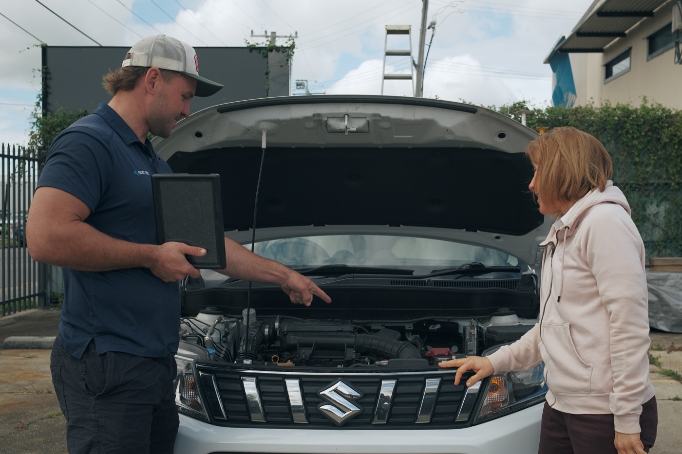 Nathan explaining a completed roadworthy inspection to a customer beside their car